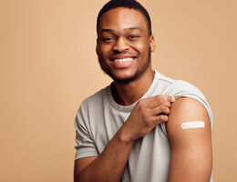 A man raises his sleeve to show his bandage.