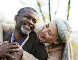 A smiling woman hugs a smiling man.